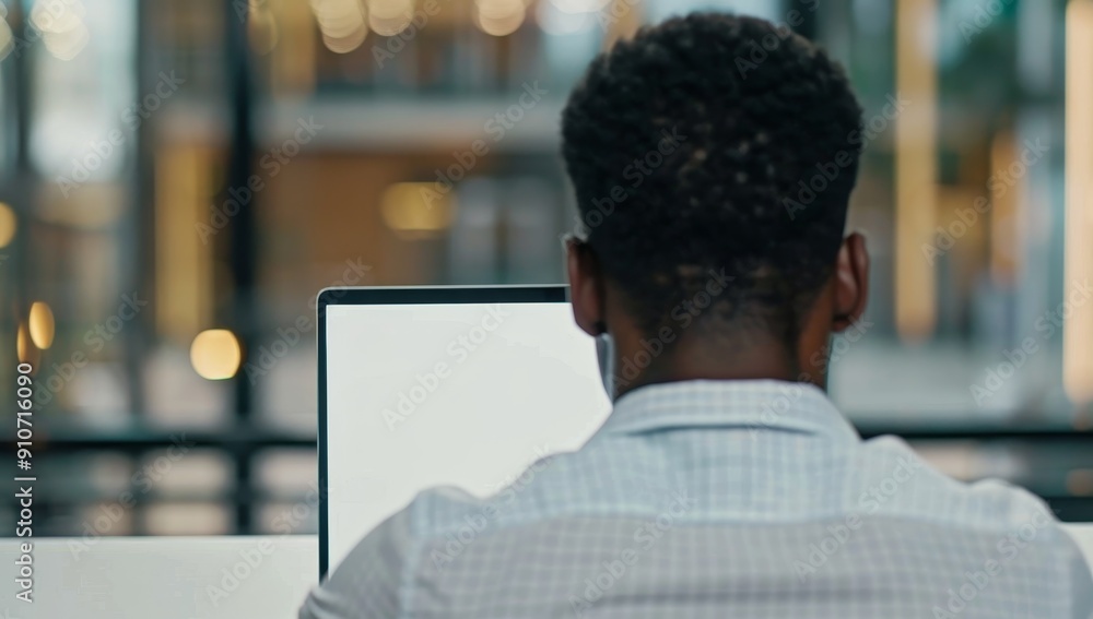 Poster Back View of a Man Working on a Laptop in an Office Setting