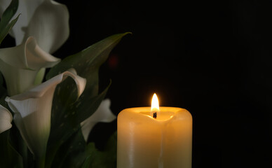 Burning wax candle in close up and white calla lily