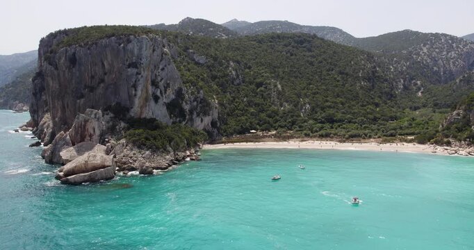 Boats And People On A Beautiful Beach With Large Cliffs In Sardinia, Italy. Paradise Travel Destination.