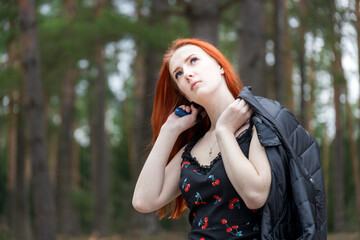 A woman with red hair is wearing a black dress and a black jacket