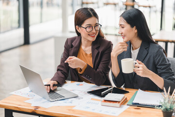 Obraz premium Two young Asian businesswomen discuss new startup project idea presentation, analyzing planning, financial statistics, and investment market at office.