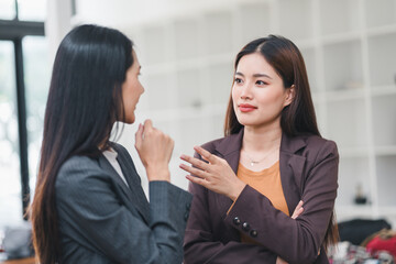 Two Asian Businesswomen Gossiping in the Office.
