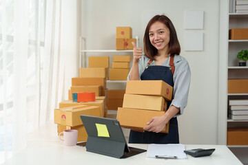 Small startup business, SME owner, female entrepreneur working, standing holding a parcel box. Checking orders online To prepare to pack boxes for sale Delivered to customers online business ideas.