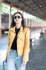 young woman is walking with suitcase at railway stations,using the smartphone and map, traveling by train.