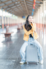 young woman is walking with suitcase at railway stations,using the smartphone and map, traveling by train.