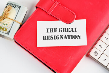 Text THE GREAT RESIGNATION, mass voluntary exodus from the workforce. THE GREAT RESIGNATION on a business card on a red notebook with dollars and a calculator lying next to it