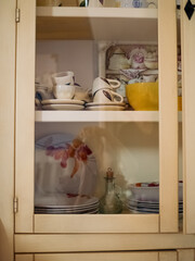 Vintage Charm: Vertical Close-Up of a White Kitchen Cabinet with Glass Doors in a Sardinian Rental.