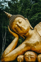 Close up of Reclining Buddha gold statue face with mountain background inThailand.