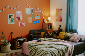 No people wide shot of modern teenagers bedroom interior with comfortable bed, posters and lights...
