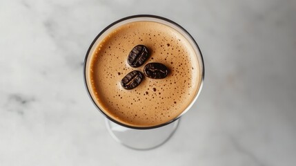 Top-down view of an Espresso Martini with a garnish of three coffee beans on a marble background