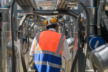 Engineers inspect gas and water pipes for power and cooling in industrial and building systems. workers in safety gear work seriously in oil and gas refining plant with pipes connecting to machinery.