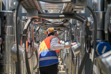 Engineers inspect gas and water pipes for power and cooling in industrial and building systems. workers in safety gear work seriously in oil and gas refining plant with pipes connecting to machinery.