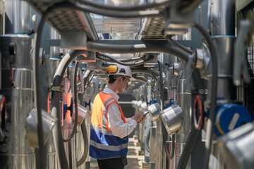 Engineers inspect gas and water pipes for power and cooling in industrial and building systems. workers in safety gear work seriously in oil and gas refining plant with pipes connecting to machinery.