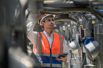 Engineers inspect gas and water pipes for power and cooling in industrial and building systems. workers in safety gear work seriously in oil and gas refining plant with pipes connecting to machinery.