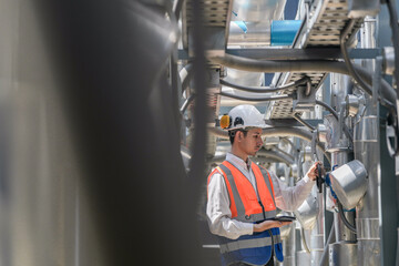 Engineers inspect gas and water pipes for power and cooling in industrial and building systems. workers in safety gear work seriously in oil and gas refining plant with pipes connecting to machinery.