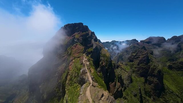 Aerial view of Pico do Pico trail following narrow ridge above steep cliffs. Popular tourist hiking destination on Madeira Island, Portugal. Drone view.