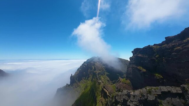 Beautiful blue sky, rugged landscape of Madeira Island with soft white clouds over Pico do Pico trail. Aerial view from drone, forward flight.