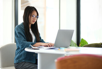 A woman is sitting at a table with a laptop in front of her