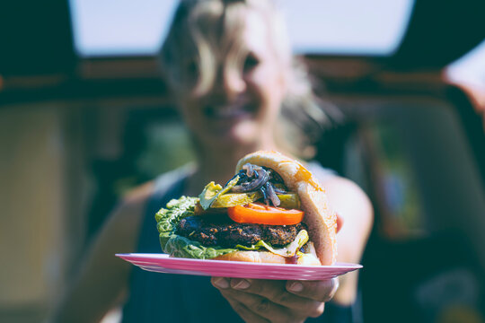 Healthy Kitchen - smiling woman shows vegan burger to the camera