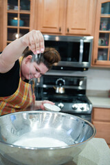 Woman sprinkling salt into a mixing bowl in the kitchen.