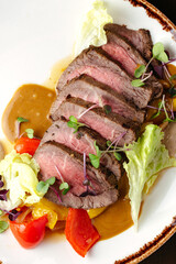 grilled beef tenderloin in a plate with sauce and side dish