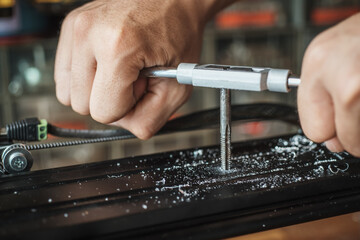 Man use screw hand tap cutting tool. tap and drill bit making hole in aluminum rail .selective focus
