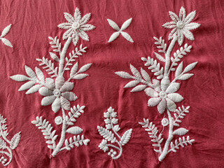 Intricate white thread embroidered floral butta on red cotton fabric