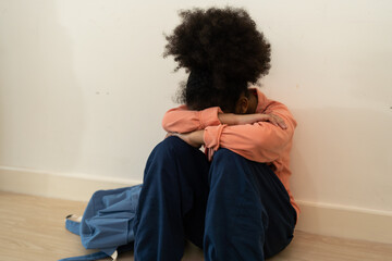 Unhappy child sitting on the floor in a school, expressing sorrow and isolation, capturing the essence of bullying and emotional distress