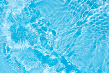 Blue water with ripples on the surface. Defocus blurred transparent blue colored clear calm water surface texture with splashes and bubbles. Water waves with shining pattern texture background.