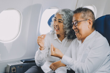 .A mature couple enjoys a plane ride sitting near the window. They looked out into the sky. Immerse yourself in the scenery and excitement of the journey. To create precious memories together