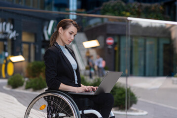 Businesswoman with a disability who uses a wheelchair working outside on a laptop
