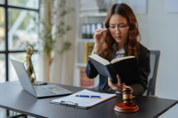 A bespectacled lawyer or legal consultant working at the level of justice sits at a table and holds a pen to view information. Detailed content about jurisprudence to study in the field of law.