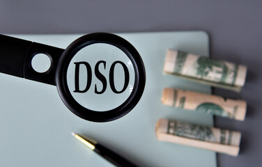 The letters DSO under a magnifying glass on the background of banknotes
