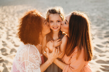 Portrait three generations beautiful Spanish women at beach kissing
