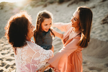 Three generation happy women hugging beach on summer day