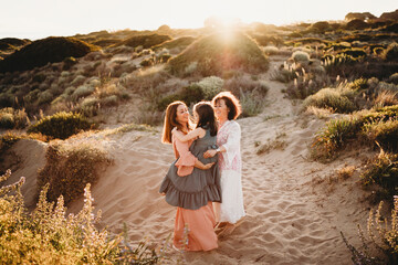 Three generations of women dancing at beach on summer day