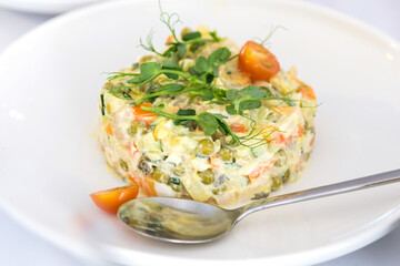 Olivier salad on a white plate. Restaurant dishes at the reception.