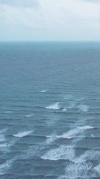 Vertical aerial shot of Dark clouds over ocean during monsoon season. Ocean waves at Mandvi beach, Kutch, India. Nature landscape. Travel background.
