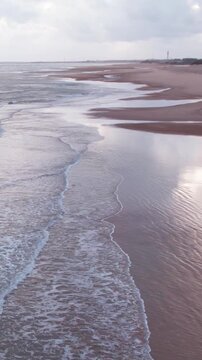 Vertical Aerial view of tropical sandy beach at Mandvi, Kutch, India. Beach waves and clouds in sky during monsoon season. Bird Eye View 4K Cinematic Drone Footage. Travel and holidays concept.
