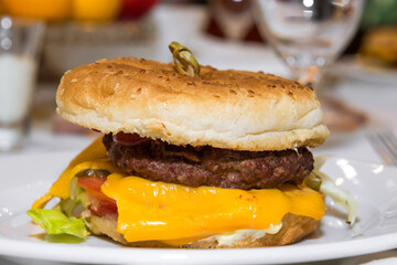 A popular American burger with minced beef, lettuce leaves, tomatoes, cheese, served in a soft bun. Freshly baked sandwich sprinkled with sesame seeds. delicious burger, burger menu, fast food.