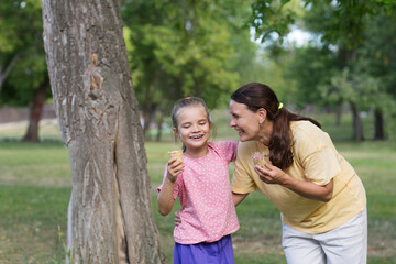 Fototapeta premium Happy family mom and child daughter eats ice cream having fun and doing picnic outdoor at city park on the green grass in summer day. Happy childhood. copy space