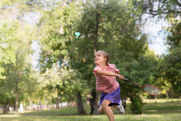 joyful little girls playing badminton, having fun in the park on sunny summer day. Childhood summer time. Kid girl with racket and shuttlecock .
