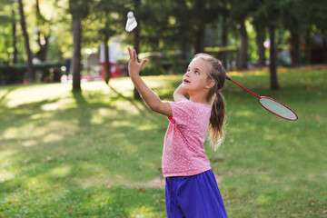 joyful little girls playing badminton, having fun in the park on sunny summer day. Childhood summer time. Kid girl with racket and shuttlecock .
