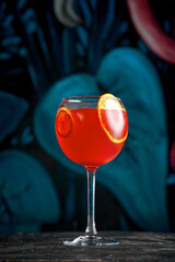 Exotic Red Cocktail garnished with a lime slice and a decorative leaf, presented in an elegant glass against a dark background