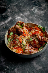 A bowl of beef teriyaki with rice, cherry tomatoes, and microgreens. The dish is served in a gray bowl on a dark background.