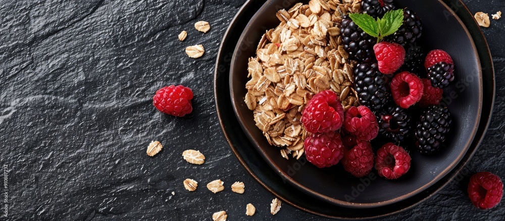 Poster fresh granola oatmeal with blackberries and raspberries beautifully arranged on a black slate backgr