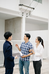 Fototapeta premium Asian man Real estate broker agent showing a house detail in her file to the young Asian couple lover looking and interest to buy it.