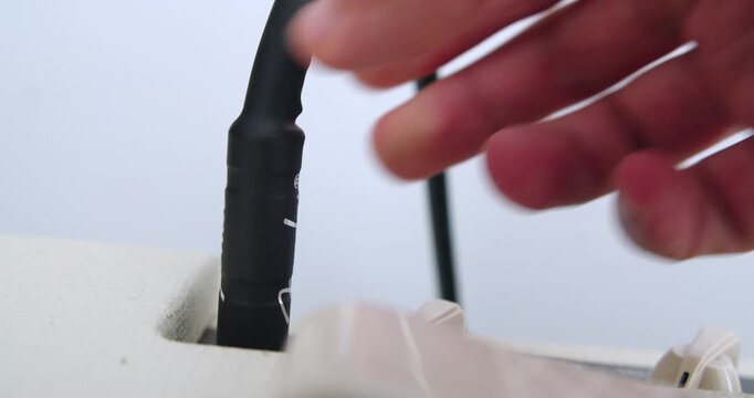 Beautiful slow motion close-up shot of a man's hand plugging a Fender plug cable into a Vox Pathfinder 10 amplifier input in a home studio in the morning.