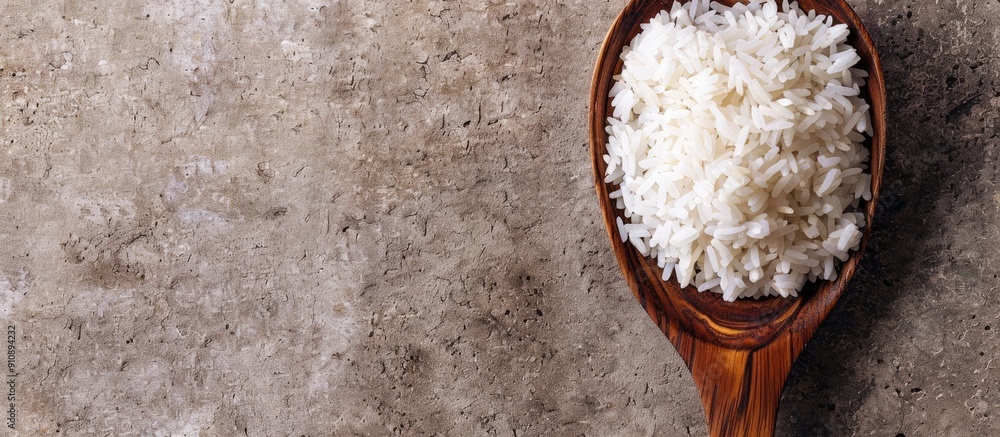 Poster a wooden spoon holds jasmine rice on a rice background creating a lovely copy space image
