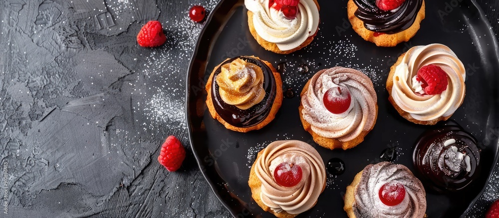 Poster top view of profiteroles and eclairs on a black matte plate with ample copy space image